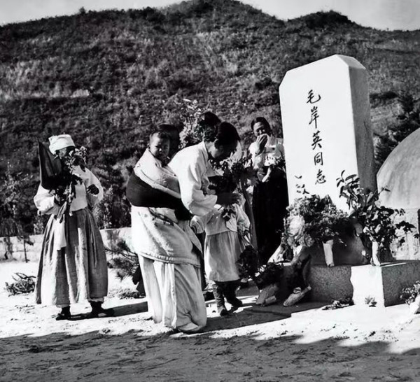 一位背着孩子的朝鲜妇女,在毛岸英烈士墓前献上鲜花。一边的人们无不垂泪
